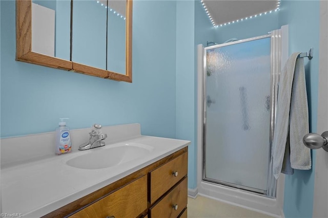 bathroom featuring a shower with door and vanity