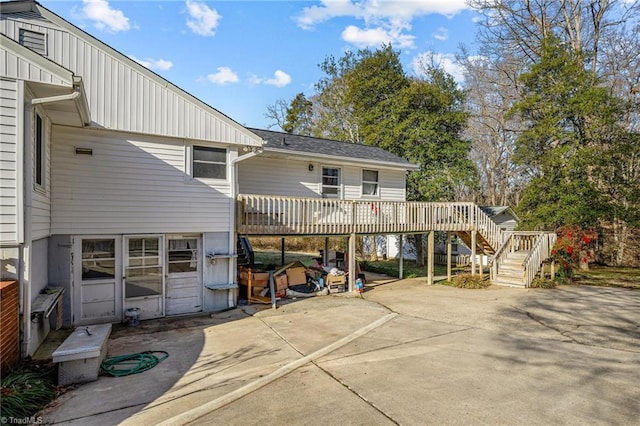 rear view of property featuring a wooden deck and a patio