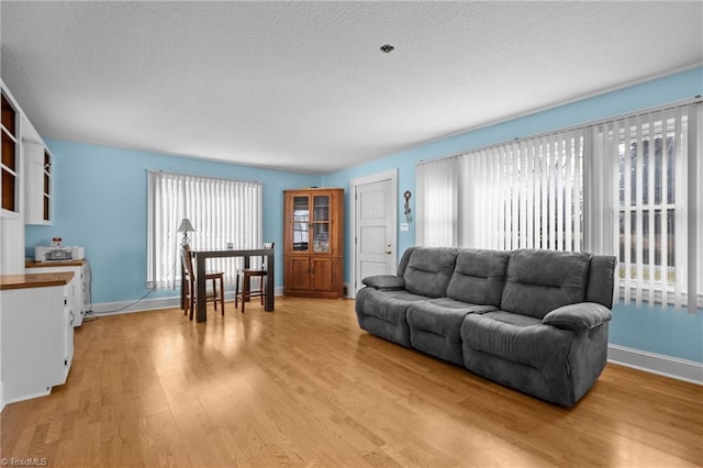 living room with plenty of natural light, a textured ceiling, and light wood-type flooring