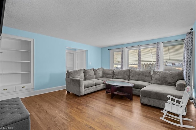 living room with hardwood / wood-style flooring, built in shelves, and a textured ceiling