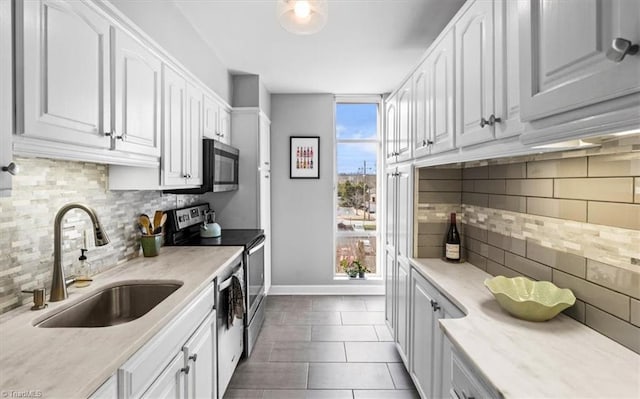 kitchen featuring sink, dark tile patterned floors, stainless steel appliances, tasteful backsplash, and white cabinets