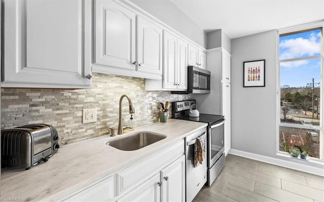 kitchen featuring white cabinetry, appliances with stainless steel finishes, sink, and decorative backsplash