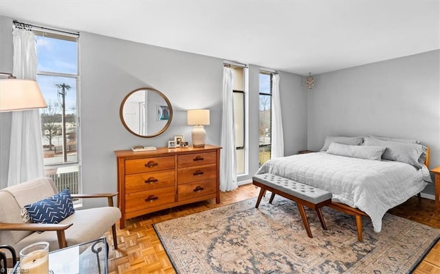 bedroom with access to exterior, a wall of windows, and light parquet flooring