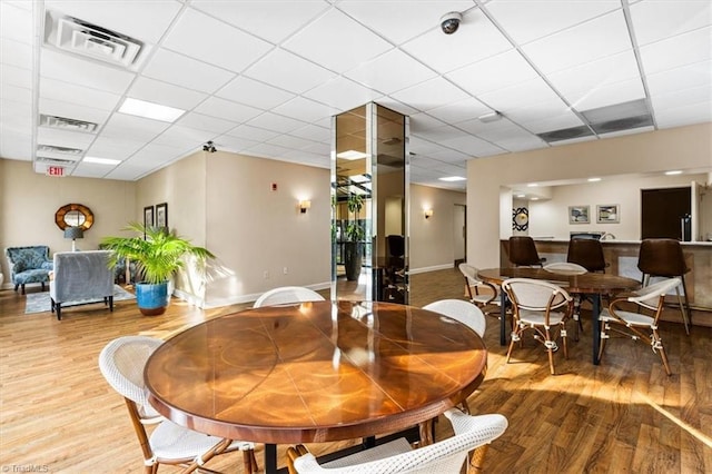 dining area featuring wood-type flooring and a drop ceiling