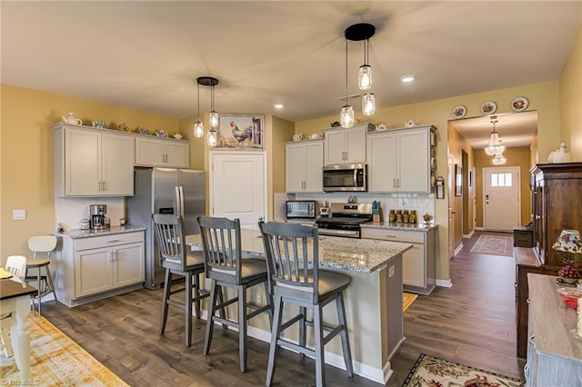 416 Bryson Blvd, Lexington, NC 27295 - kitchen featuring stainless steel appliances, dark wood-style flooring, a kitchen bar, hanging light fixtures, and light stone countertops