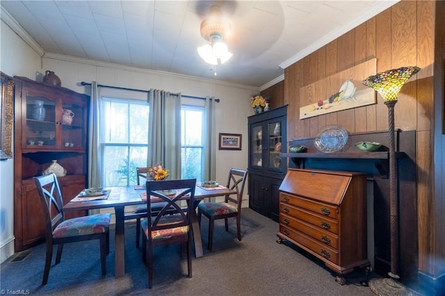 carpeted dining area featuring ornamental molding and wooden walls