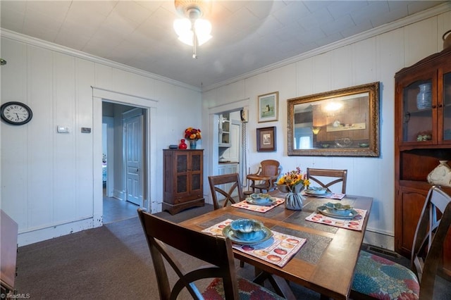 dining space with ornamental molding and dark colored carpet