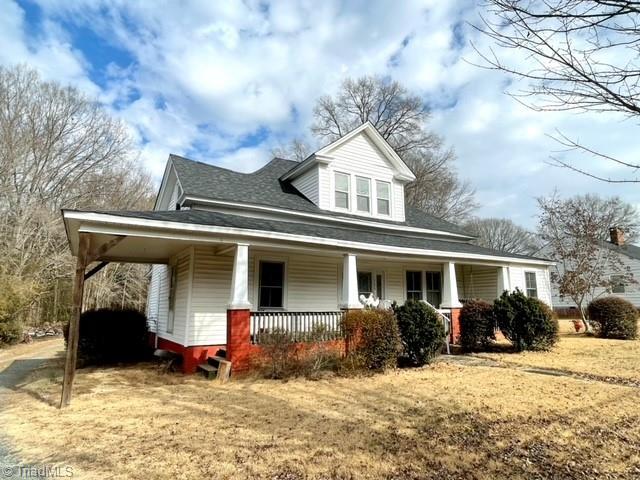 farmhouse inspired home with covered porch and a front lawn