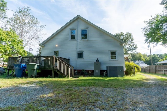 rear view of house featuring a wooden deck, a yard, and central air condition unit