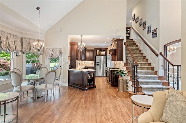 4607 Eden Bridge Dr, Kernersville, NC 27284 - living room with a chandelier, high vaulted ceiling, stairway, and light wood-style floors