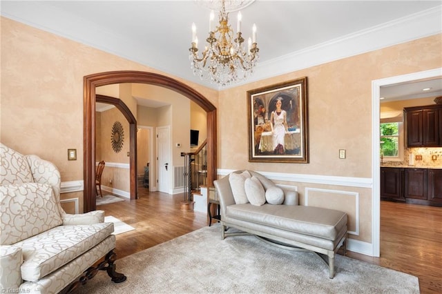 4607 Eden Bridge Dr, Kernersville, NC 27284 - sitting room with arched walkways, wood finished floors, a chandelier, ornamental molding, and a wainscoted wall