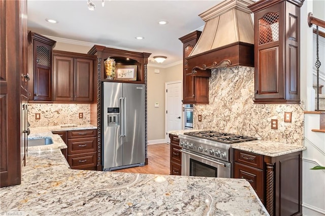 4607 Eden Bridge Dr, Kernersville, NC 27284 - kitchen featuring high quality appliances, light stone counters, decorative backsplash, custom range hood, and ornamental molding