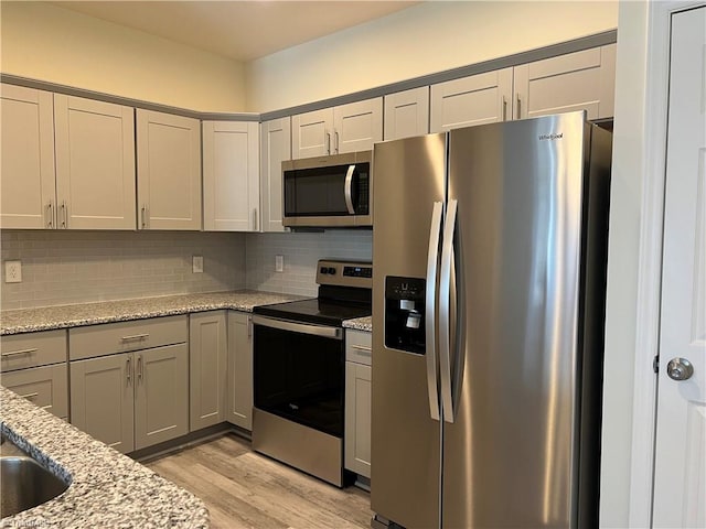 2607 Pennoak Way Unit H, Greensboro, NC 27407 - kitchen featuring stainless steel appliances, gray cabinets, light wood finished floors, tasteful backsplash, and light stone counters