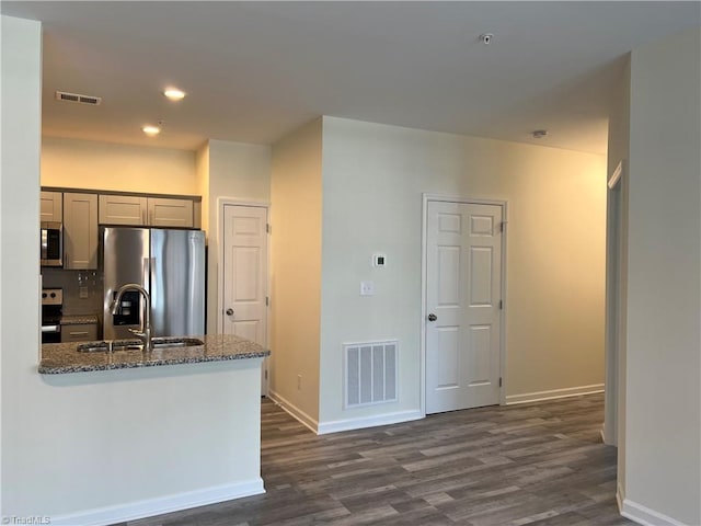 2607 Pennoak Way Unit H, Greensboro, NC 27407 - kitchen featuring stainless steel appliances, dark wood finished floors, dark stone countertops, a peninsula, and recessed lighting