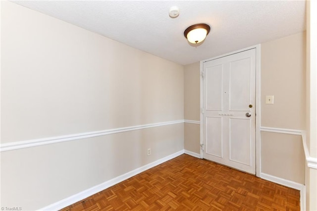 unfurnished room featuring a textured ceiling and baseboards