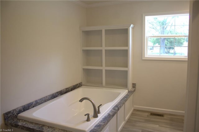 bathroom with a bathing tub, crown molding, and hardwood / wood-style floors