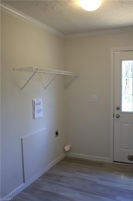 laundry area featuring wood-type flooring, a textured ceiling, ornamental molding, and electric dryer hookup