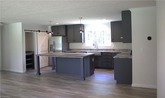 kitchen featuring a textured ceiling, sink, a barn door, a kitchen island, and hanging light fixtures