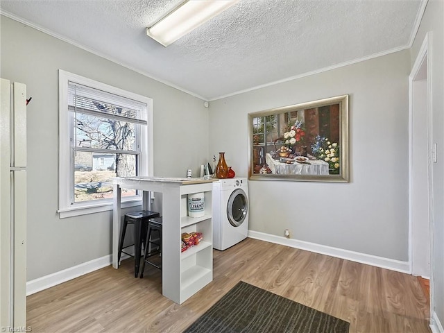 laundry room with washer / dryer, a textured ceiling, baseboards, and wood finished floors