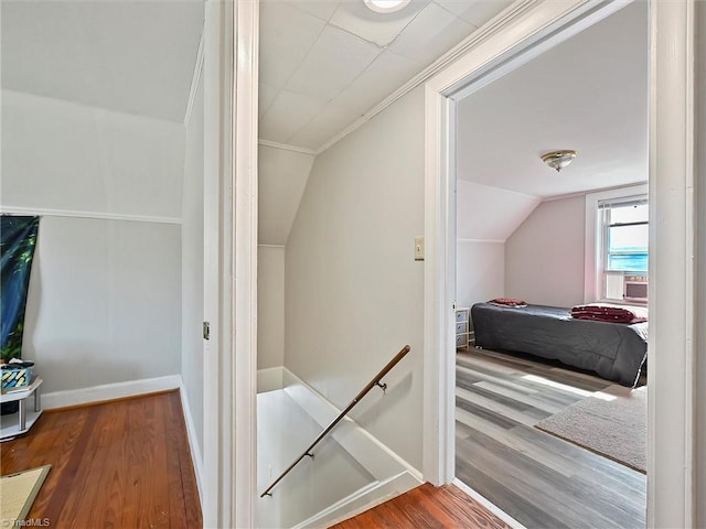 interior space with vaulted ceiling, wood finished floors, an upstairs landing, and baseboards