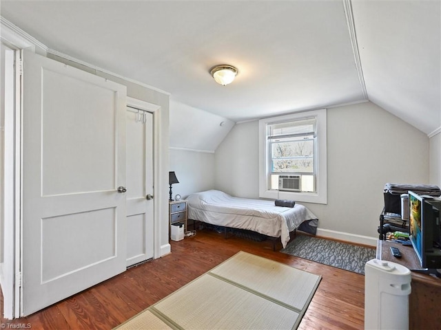 bedroom with cooling unit, vaulted ceiling, baseboards, and wood finished floors