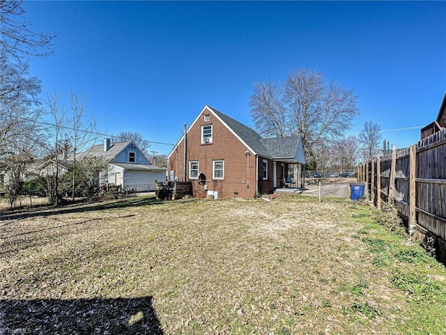 back of house with a yard, crawl space, brick siding, and fence