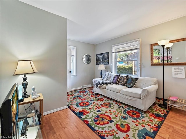 living area with visible vents, light wood-style flooring, and baseboards