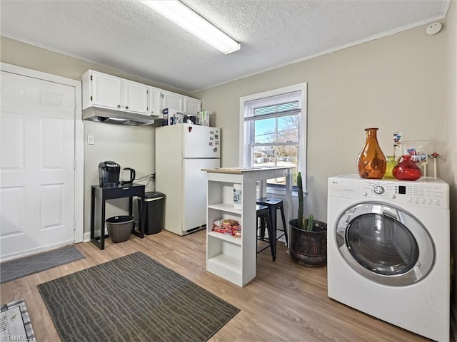 clothes washing area featuring washer / dryer, light wood-type flooring, crown molding, and a textured ceiling