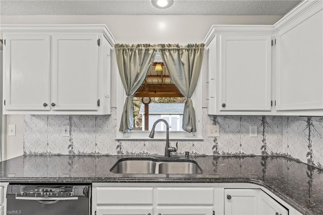 kitchen featuring dishwasher, sink, dark stone countertops, and white cabinets