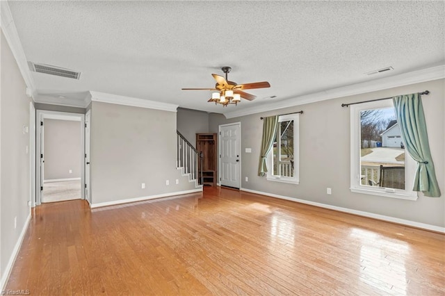 empty room featuring ceiling fan, ornamental molding, light hardwood / wood-style floors, and a textured ceiling