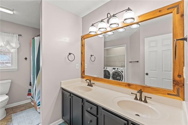 bathroom with tile patterned flooring, vanity, independent washer and dryer, and toilet