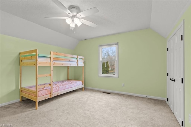 carpeted bedroom with lofted ceiling, a textured ceiling, and ceiling fan