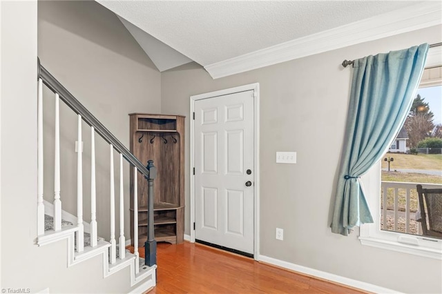 entrance foyer featuring lofted ceiling, crown molding, wood-type flooring, and a textured ceiling