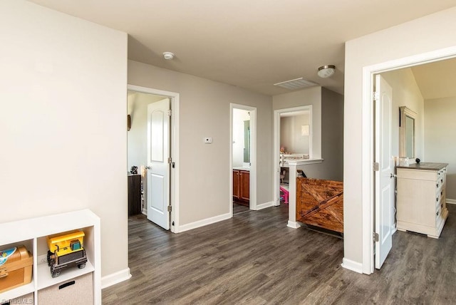 hallway with visible vents, baseboards, and dark wood-style flooring