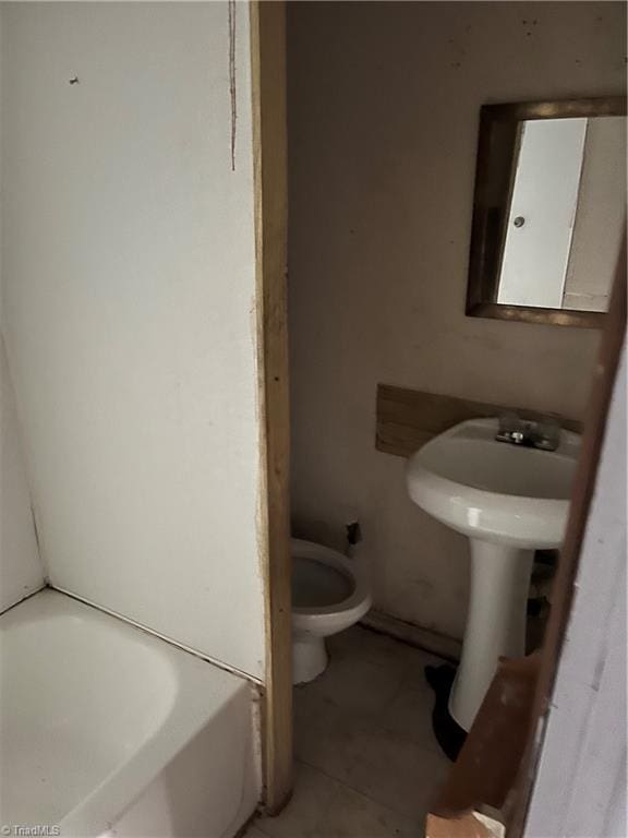 bathroom featuring tile patterned floors, toilet, and a tub to relax in