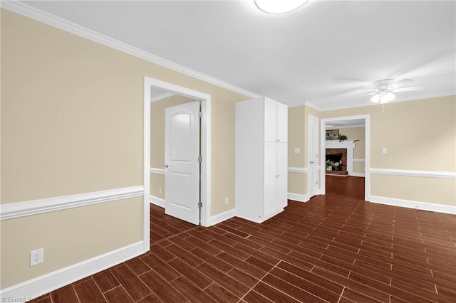 2305 Hunters Ridge Dr, Pleasant Garden, NC 27313 - unfurnished room with baseboards, ceiling fan, a fireplace with raised hearth, dark wood-type flooring, and crown molding