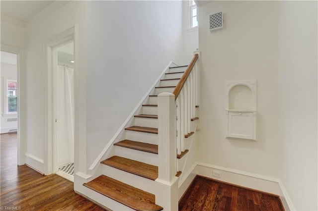 stairs with crown molding, wood finished floors, visible vents, and baseboards