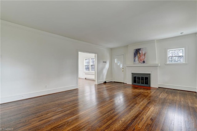 unfurnished living room with a brick fireplace, crown molding, baseboards, and wood finished floors