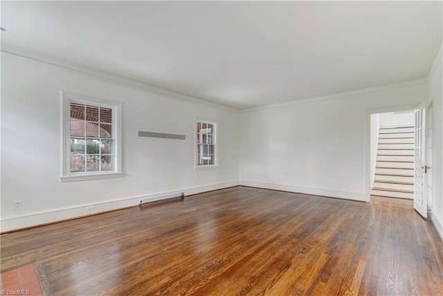 empty room with wood finished floors, baseboards, visible vents, stairs, and crown molding