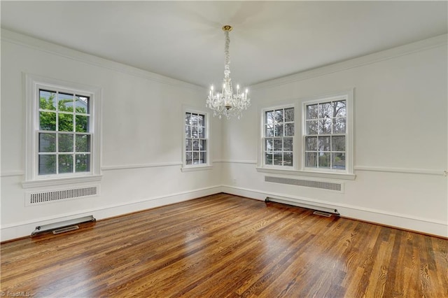 spare room with a wealth of natural light, visible vents, wood finished floors, and ornamental molding