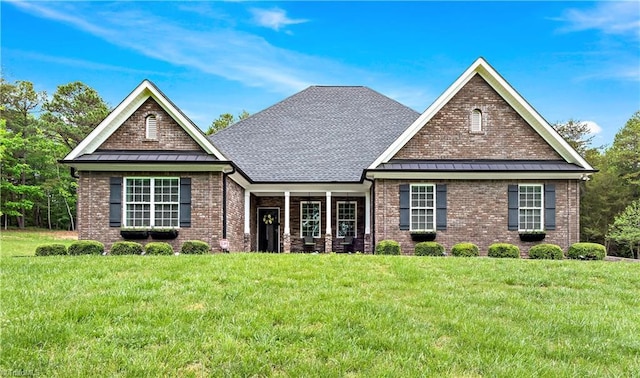 view of front facade with a standing seam roof, brick siding, and a front yard