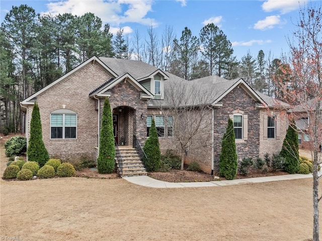 view of front of home with brick siding and roof with shingles