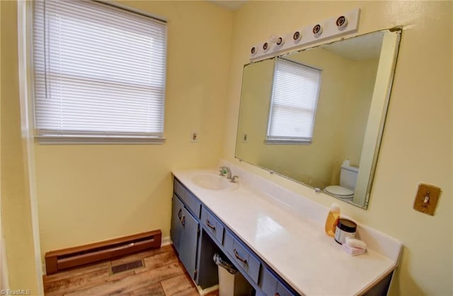 bathroom featuring vanity, a healthy amount of sunlight, a baseboard radiator, and toilet