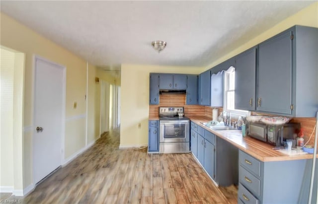 kitchen with tasteful backsplash, sink, electric range, blue cabinetry, and light wood-type flooring