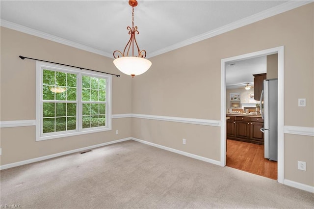 empty room featuring light carpet, crown molding, and baseboards