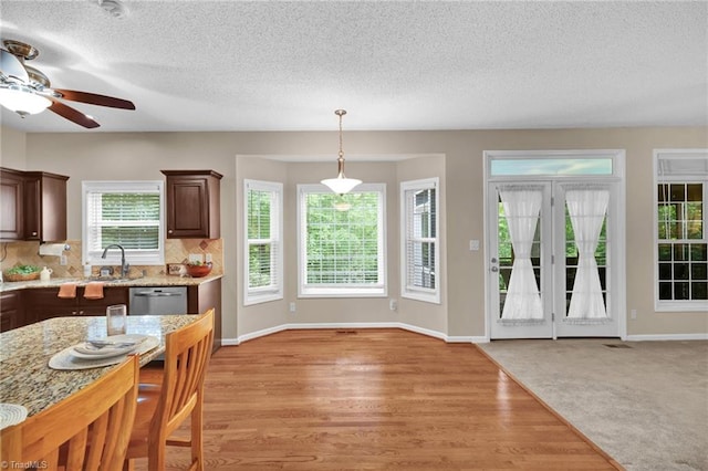 kitchen with stainless steel dishwasher, a ceiling fan, a textured ceiling, backsplash, and baseboards