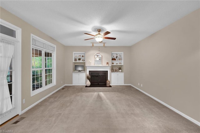 unfurnished living room with a fireplace with flush hearth, carpet floors, a textured ceiling, ceiling fan, and baseboards