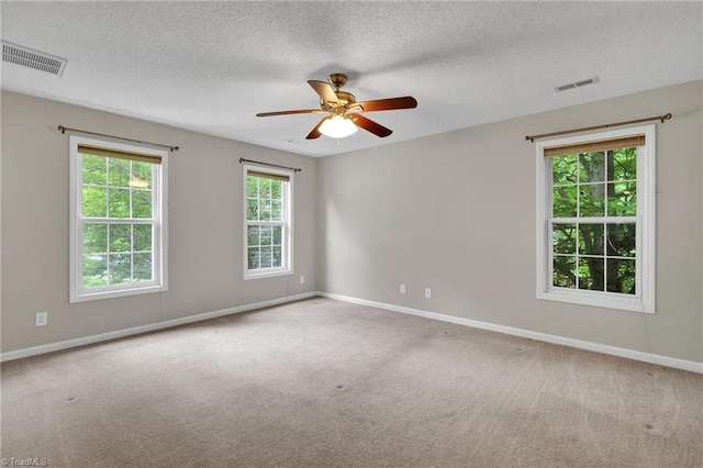 spare room with carpet, baseboards, a ceiling fan, and a textured ceiling