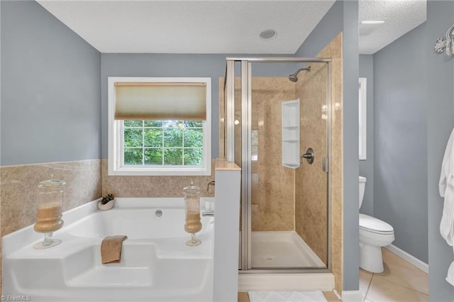 full bath featuring a shower stall, a garden tub, tile patterned floors, a textured ceiling, and toilet