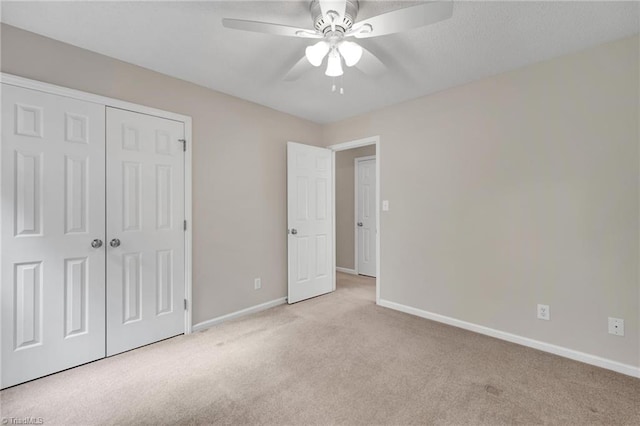 unfurnished bedroom with carpet floors, baseboards, a closet, and a ceiling fan
